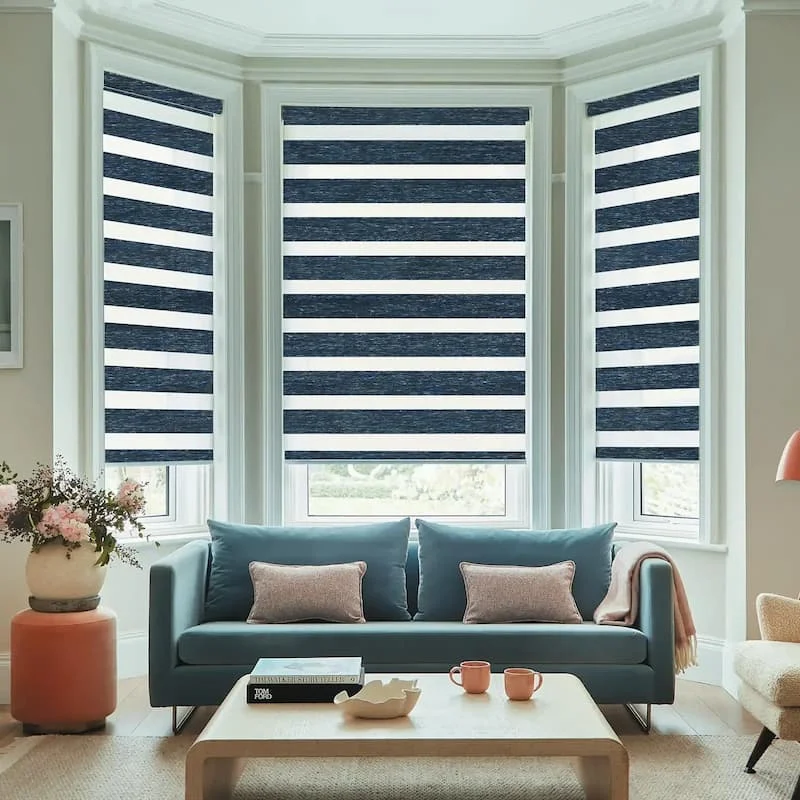 Striped day and night roller blind over a window beside a small desk