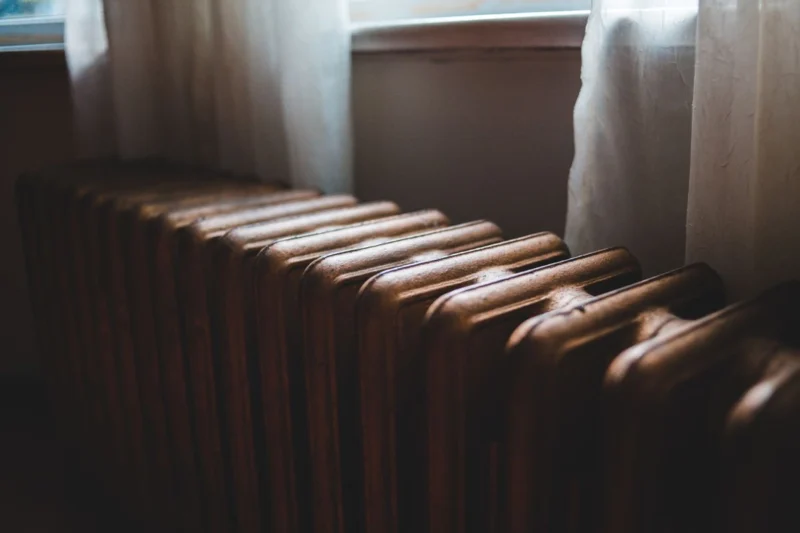 Cast iron radiator under a window with curtains