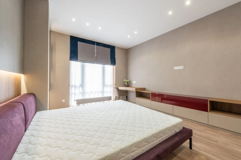 Dim-out and blackout blinds suit bedrooms like this one with a navy-edged fabric blind