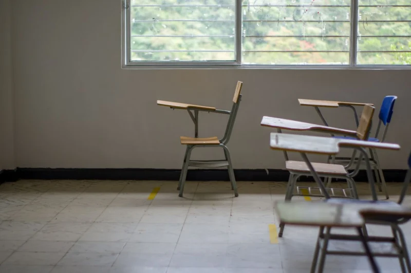 Empty classroom with desks beside large windows
