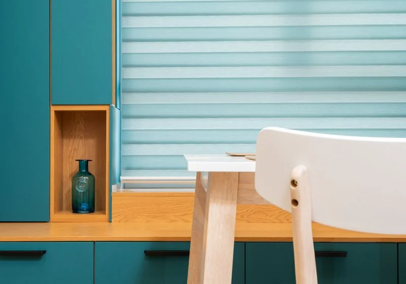 Striped day and night roller blind over a window beside a small desk