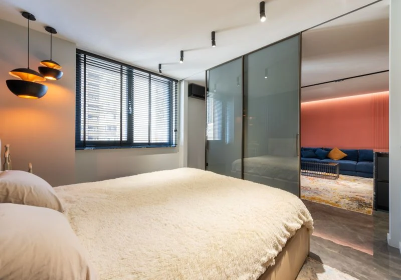 Modern bedroom with dark roller blinds on a wide window