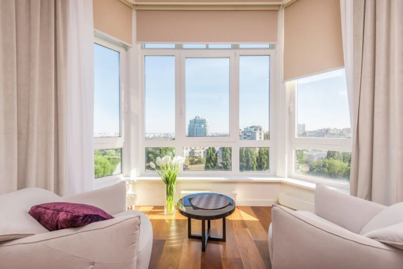 Ways to keep a south-facing room cool: a sunny bay window with white armchairs